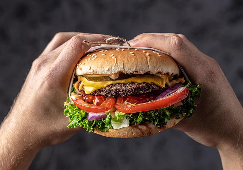 cheesy burger held in hands