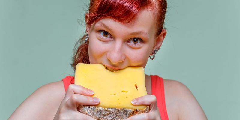 woman biting block of cheddar cheese